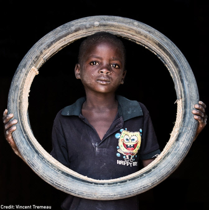 Child holding tire. Photo part of 2016 photographic exhibition in New York.